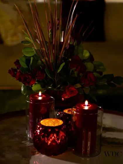 A simple yet poetic detail. A centerpiece of red roses and candles, perfect for a regal theme, because your special day deserves decor that speaks of love.