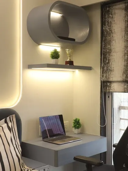 A compact work-from-home corner integrated into a master bedroom. The floating desk and curved overhead shelf provide a functional workspace without taking up valuable floor area, complemented by integrated LED lighting.