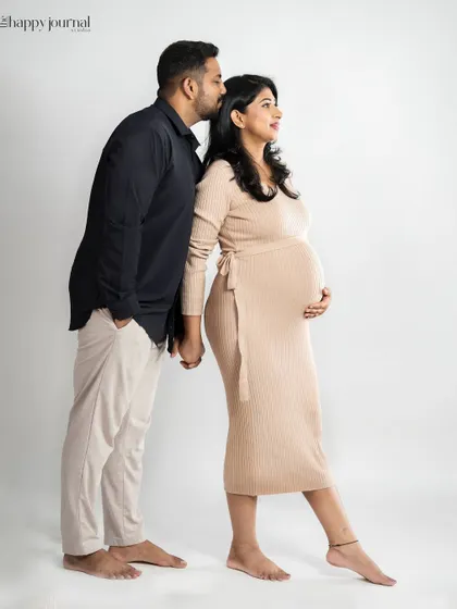 A classic pose for an expecting couple. The husband stands behind his wife, his hand on her shoulder, as they look forward to their future together.
