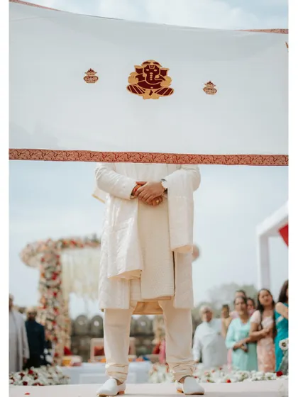 An artistic shot of the groom during the ceremony, his face partially hidden. This creative composition builds anticipation and focuses on the traditional elements of the moment.