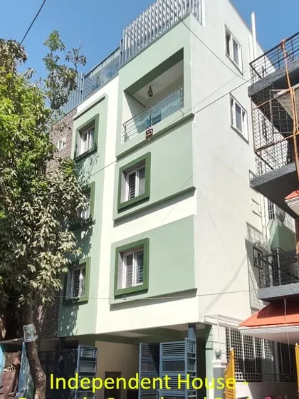 An independent house painted with a modern color-blocking scheme using sage green and white. This approach adds visual interest and highlights the building's different sections and window frames.
