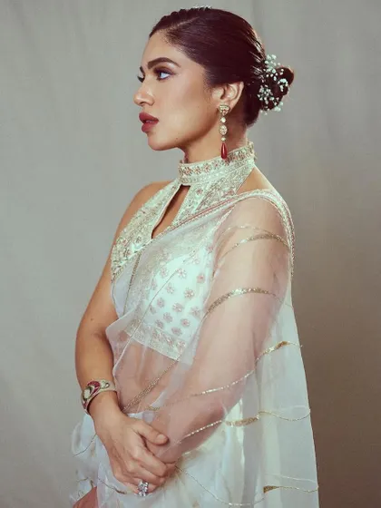 The side profile of this ivory saree look shows off the beautiful floral bun and statement earrings, proving that the back of an outfit is just as important as the front.