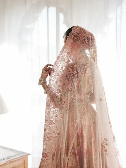 A moment of quiet reflection by the window. The soft light filtering through the veil creates an ethereal and delicate portrait.