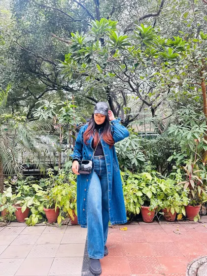 For a cooler day, I love layering denim. Here, a long denim jacket is worn over a black turtleneck and wide-leg jeans, topped off with a faux leather cap for an urban edge.