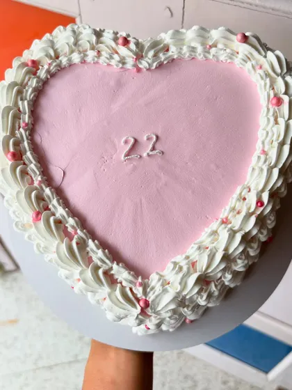 A top-down view of the pink heart-shaped cake. The simple number "22" in the center keeps the focus on the intricate piping work.