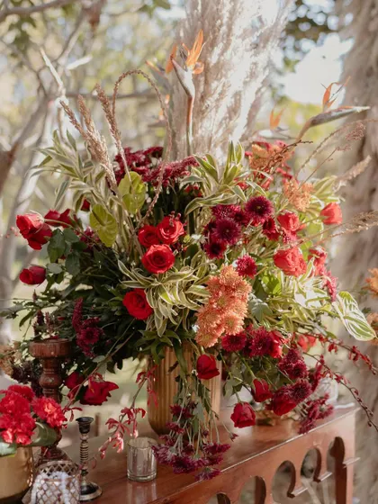 A stunning floral arrangement featuring a mix of reds, maroons, and delicate dry elements. This is how we translate a vision like 'Sabyasachi magic' into a floral story.