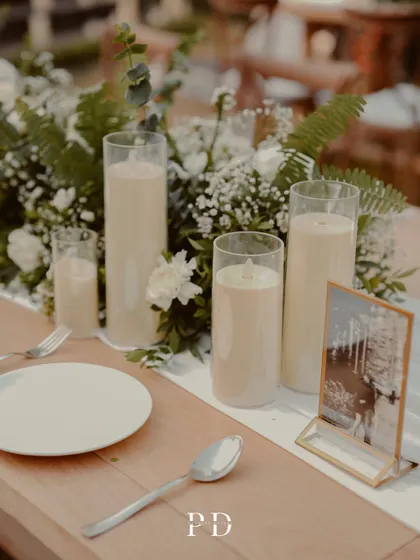 A close-up of the centerpiece, featuring pillar candles and a small framed photo of the couple. It's these personal touches that make a celebration unique.