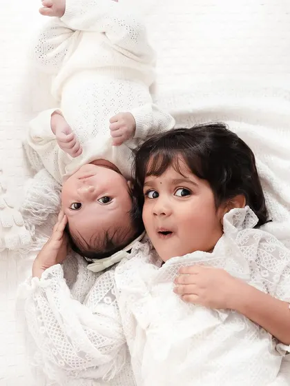 A creative and sweet pose with two sisters lying on a soft white blanket. It captures their surprise and wonder in a unique way.