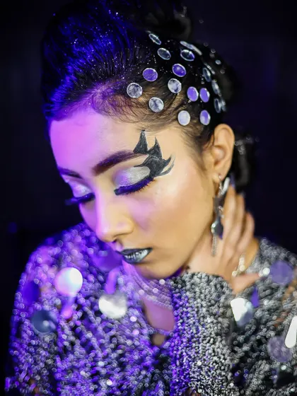 A close-up on the silver eye makeup and hair gems, highlighting the intricate details of this party look.