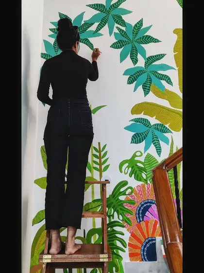 Up on a ladder to reach the top sections of this tall staircase wall. Large-scale murals like this are a fun challenge.