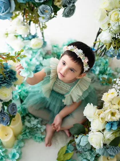 Looking up with curiosity at the floral arrangements during her tea party themed shoot.