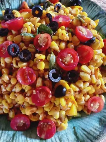 A sweet corn salad with cherry tomatoes and black olives, offering a burst of color and flavor.