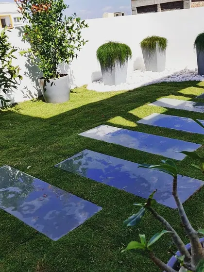 Another angle of the completed terrace garden, showing how we used reflective pavers set in the lawn to create a stylish walkway. The space is decorated with large planters and trees.