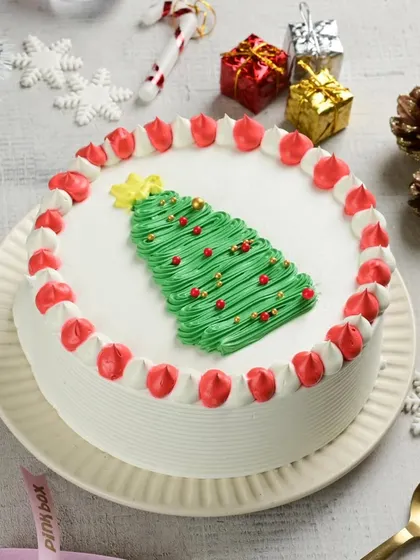 A classic Christmas cake design featuring a piped Christmas tree and a festive red and white border. It’s a simple, elegant, and delicious way to celebrate the holiday season.