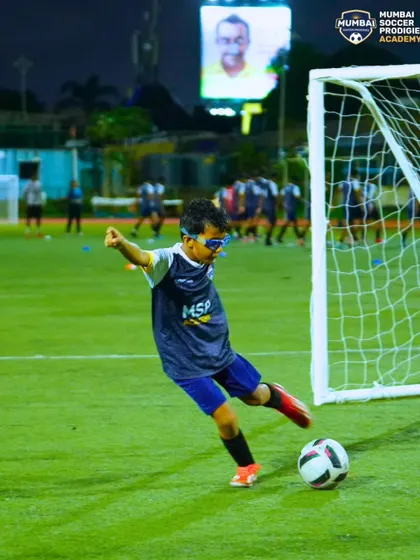 A young player practices his shooting, aiming for the goal with focus and determination.