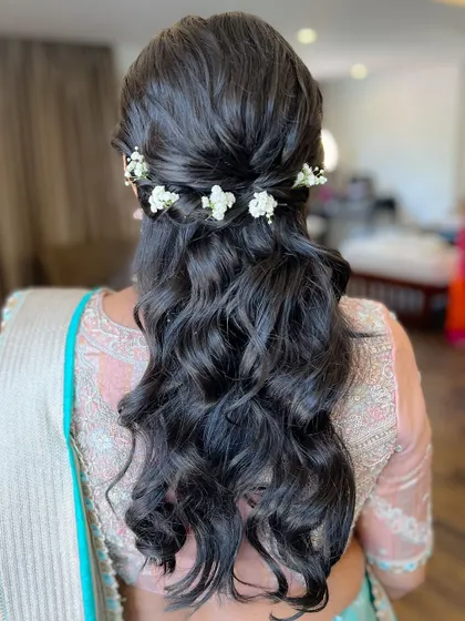 A simple half-updo with delicate white flowers, an elegant choice for any wedding guest.
