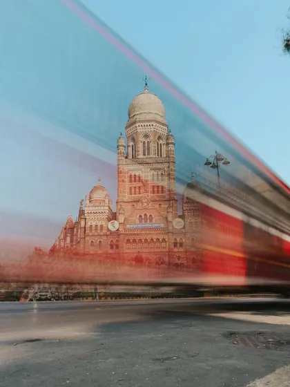 A long-exposure shot showing the motion blur of a red bus passing in front of the BMC building. This technique creates a dynamic image that contrasts movement with stillness.