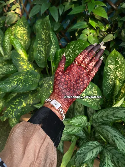 A beautiful, dark stain on a hand against a lush green background.