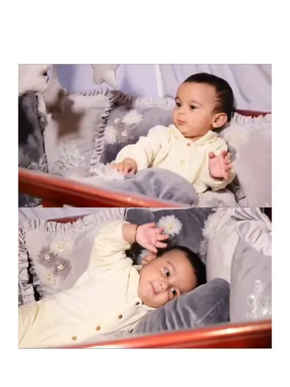 A happy baby enjoying his new cozy corner. He is sitting up and looking content in his crib, which is filled with my soft, custom-made grey velour pillows with floral details.