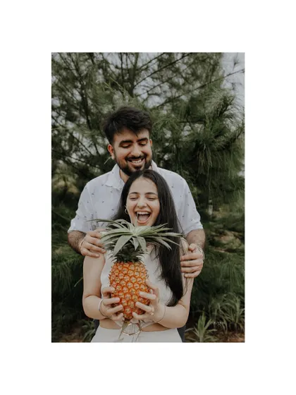 A sweet and playful pre-wedding shot in Goa, with the couple laughing while holding a pineapple.