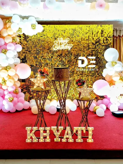 A birthday stage with a full gold sequin backdrop, creating a bright and celebratory atmosphere on a red carpet stage.