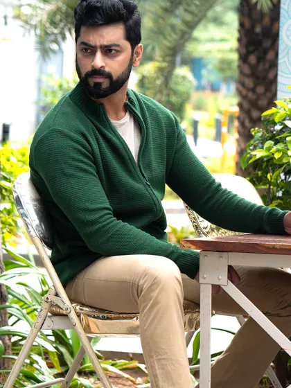 A relaxed, seated portrait of Tarak Ponnappa at an outdoor cafe. This captures a more casual and contemplative mood, adding range to his portfolio.