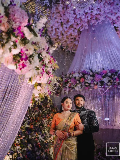 A wider shot of the couple at their lavish reception, showcasing the grand scale of the decorations and the overall opulent ambiance.