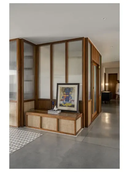 A custom-built storage bench with rattan panels, providing a place to sit and store items at the entrance. The artwork adds a personal touch.