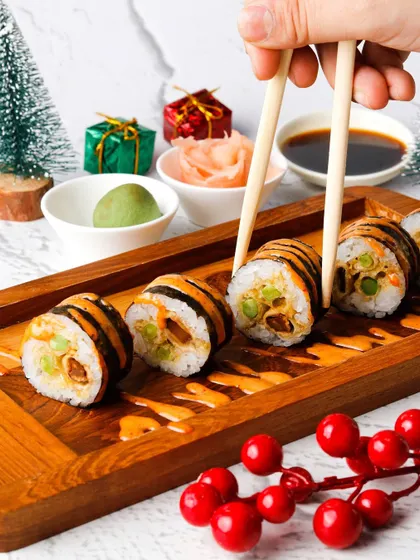 Tiger-striped sushi rolls styled with mini Christmas trees and gifts for a unique holiday menu.