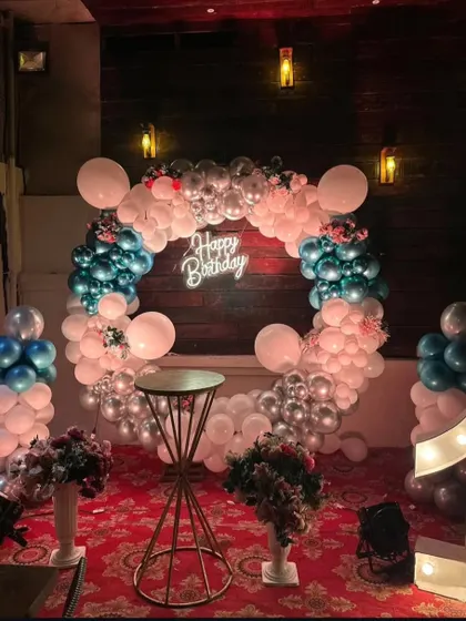 A first birthday party with a chic color scheme. The decor features a balloon ring in shades of blue, white, and silver, with a large light-up number "1" and a neon sign.