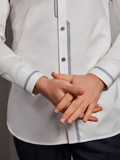 A close-up of the hands, showing the cuff and placket details of the white shirt. It’s these small touches of contrast that make the piece stand out.