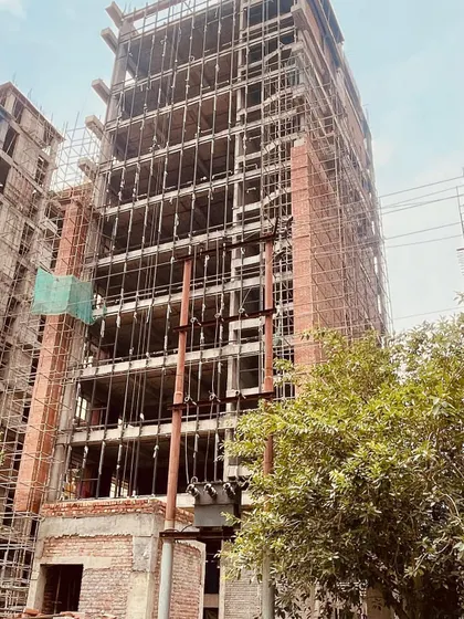 An angled shot from the construction site, showing the scale of the office tower. The image captures the building at a key phase, where the core structure is complete and the facade work is progressing.