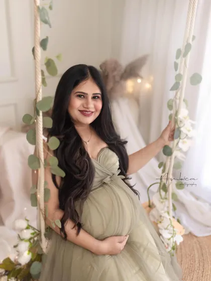 A bright and happy solo portrait on the swing. Her beautiful smile and the soft, rustic styling of the set create a warm and inviting maternity photo.