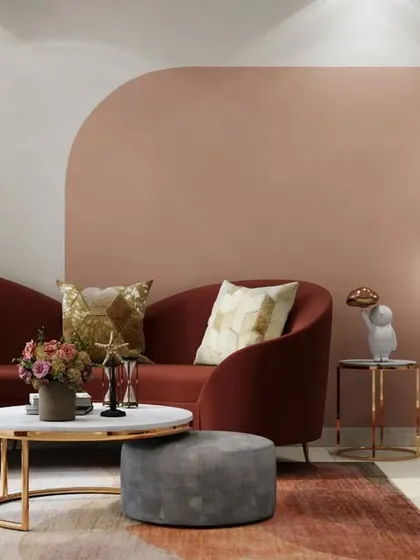 This living room uses a warm, analogous color scheme of blush pink and deep red to create a cozy and inviting atmosphere. The curved sofa and gold-accented lighting add a touch of modern elegance.