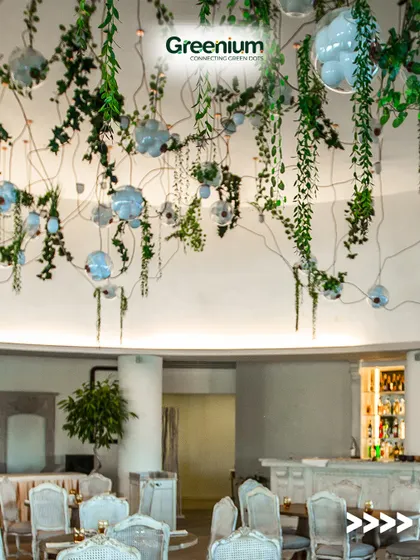 A sophisticated restaurant or cafe rooftop design. The ceiling is adorned with hanging artificial vines and modern light fixtures, creating an enchanting atmosphere for guests.