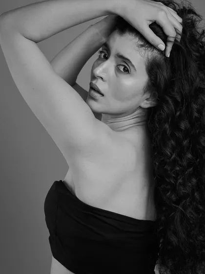 A more dramatic, moody shot showcasing long, beautiful curls. This black and white image highlights the texture and shape of the hair, creating a powerful and artistic portrait.