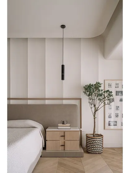 Another view of the master bedroom, showing the striped accent wall and the simple, elegant furniture arrangement.