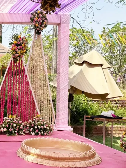 Another angle of the Haldi stage, showing the intricate work of the hanging floral curtains and the lush flower arrangements at the base.