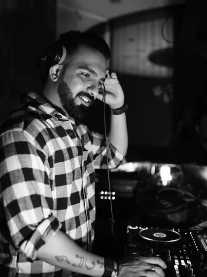 Listening closely to the next track. This black and white shot captures a classic DJ pose, a moment of preparation before the drop.