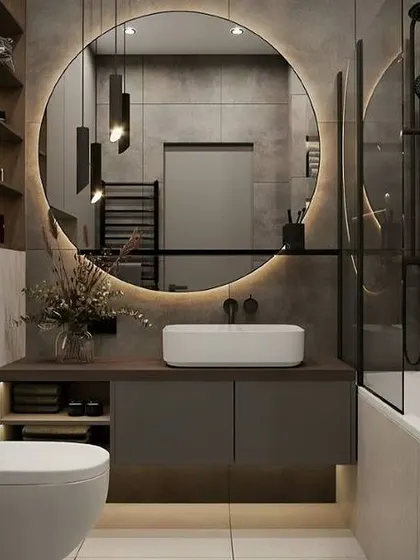 A well-balanced bathroom design with a round back-lit mirror, a floating vanity with storage, and a bathtub-shower combination.