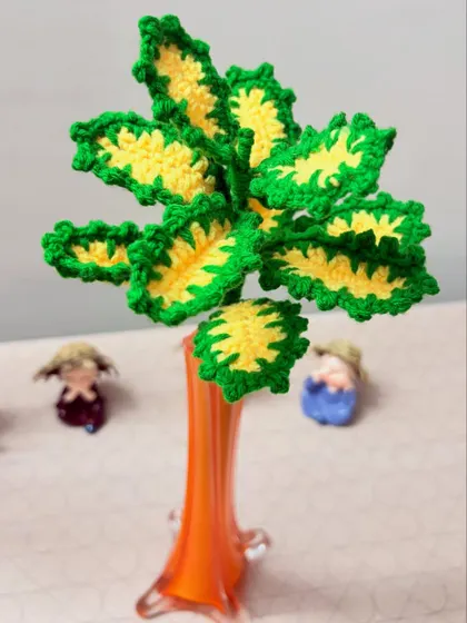 This crochet plant features bright green and yellow leaves, creating a cheerful and maintenance-free decorative piece.