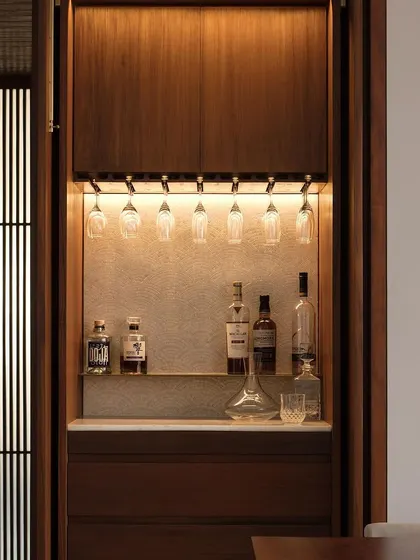 A close-up of the concealed bar unit in the Altamount Road apartment. This piece of custom cabinetry is designed with warm wood and integrated lighting, providing a functional and elegant feature for entertaining.