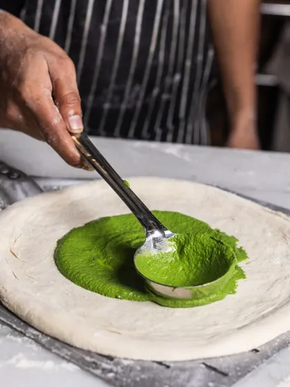Who says pizza sauce has to be red? Here, I'm spreading a vibrant spinach and mustard cream for my Mushroom and Burrata pizza, showing my creative approach to classic dishes.