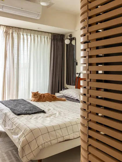 The bedroom, complete with its most important resident, Penny the cat. The wooden slat partition adds a touch of texture and creates a sense of separation without closing off the space.