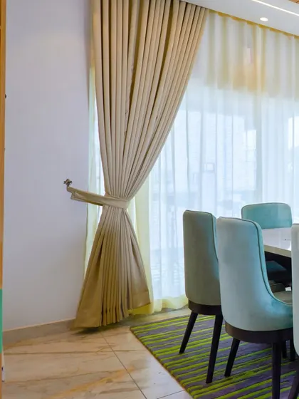 A detail shot of the elegant curtains and shelving unit in the green-themed dining room.