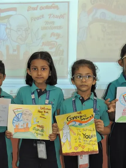 A group of students holds up their completed slogan and poster artwork, celebrating the legacy of Gandhi and Shastri.