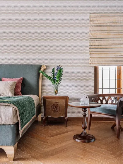 Here, we used a calm, muted color palette and natural materials to create a peaceful atmosphere. The herringbone wooden flooring adds warmth, while the traditional-style chair and side table provide a charming space for reading by the window.