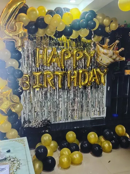 A 4th birthday party with a black and gold theme, featuring a full balloon arch and a large foil number.