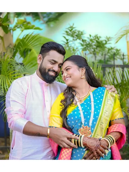 A vibrant outdoor portrait of a couple in colorful traditional Maharashtrian attire. Their happy embrace and bright outfits make for a joyful and culturally rich photo.