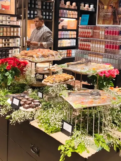Our grazing table at Bath & Body Works on 100 feet Road pairs small bites with red roses, greenery and serving stands.